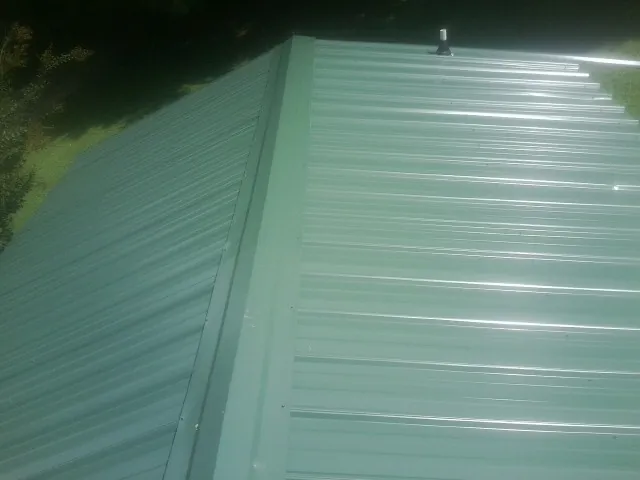 New green metal panels meeting at the ridge of a roof — Flat Roof Repair work by our crew in Withams