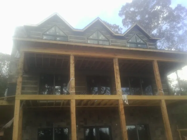 Dormers and porch framing on a large log home under construction — Roof Coating work by our crew in Withams