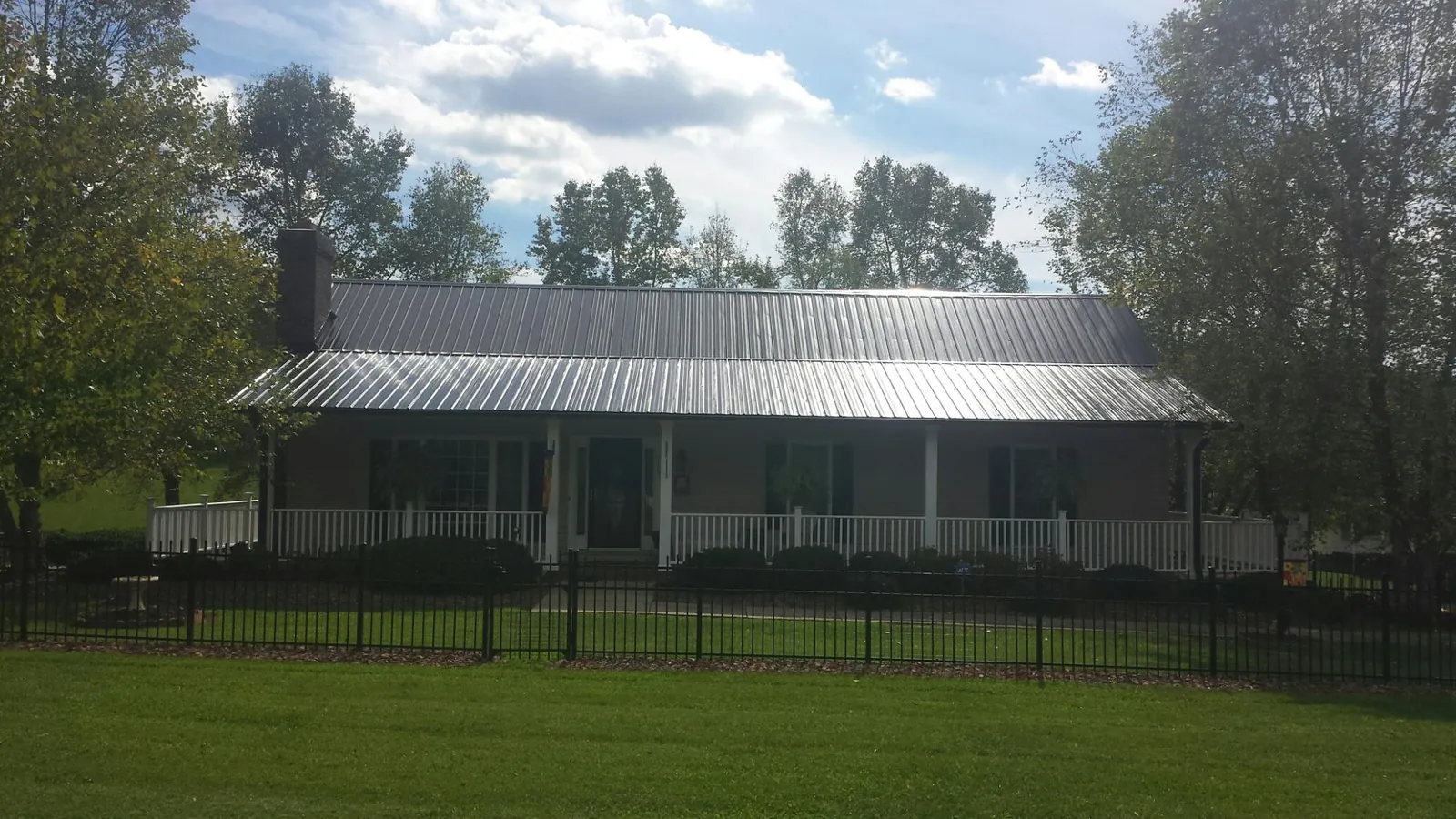 Gray metal roof on a brick ranch with a full width front porch — Gutter Guard Installation work by our crew in Withams