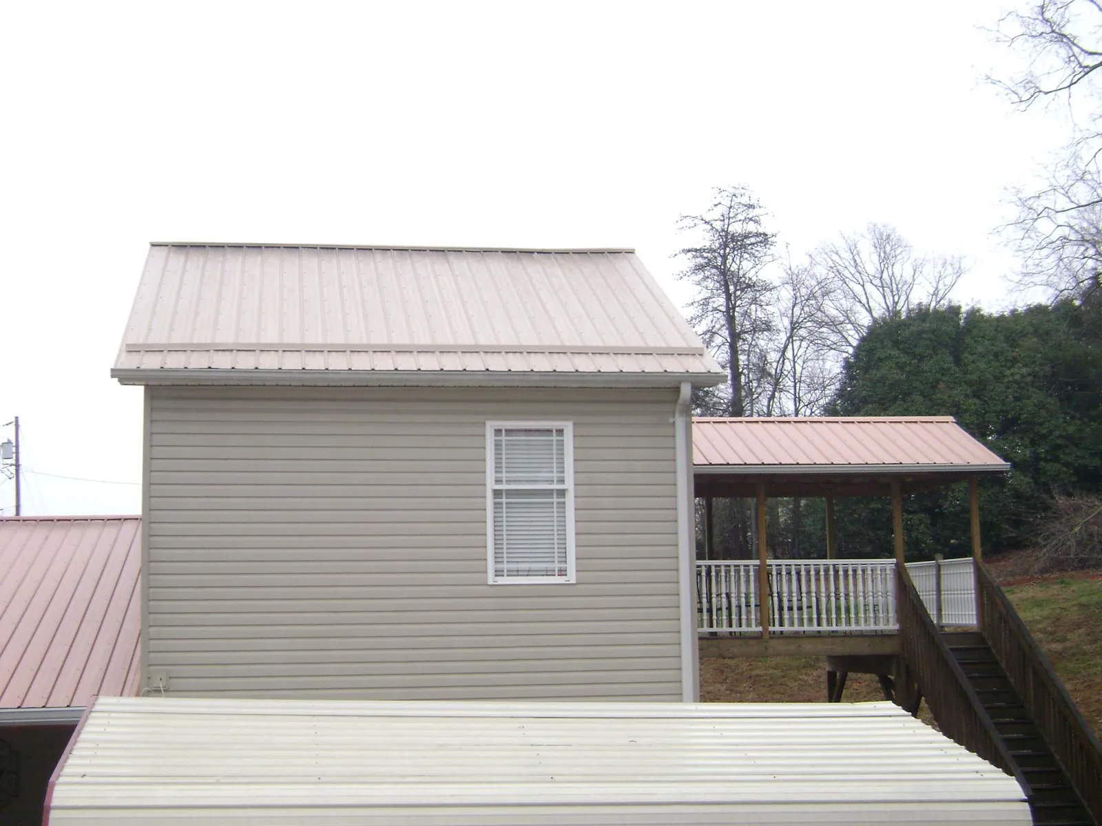 Tan metal roofs on a two story addition and attached porch, from a Roof Replacement job in Withams